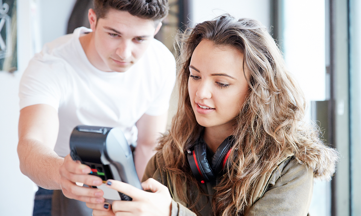 Man holding a chip and pin device while a woman inputs security code